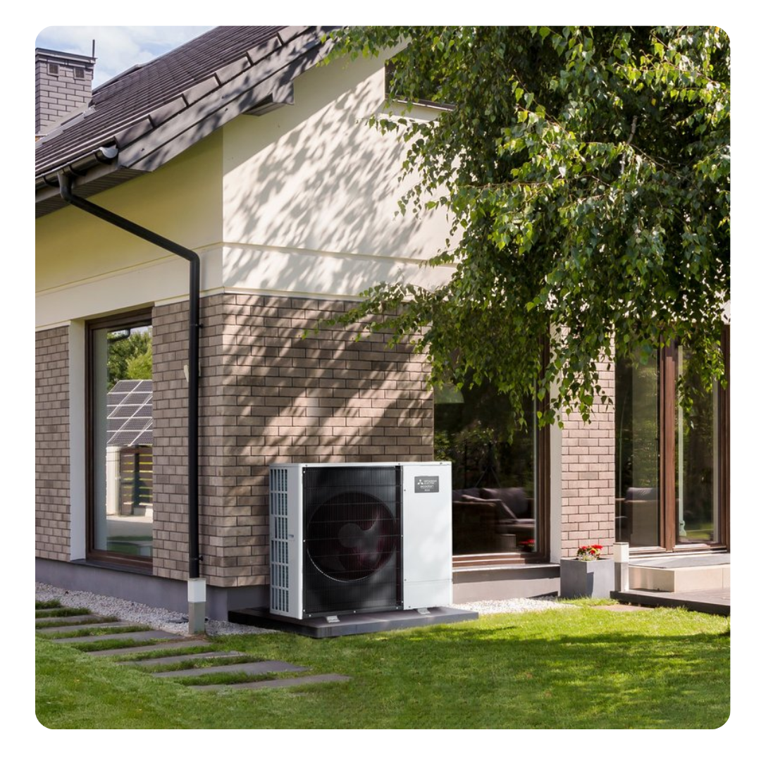 Mitsubishi heat pump outside a modern house with greenery - Heat Pump Service